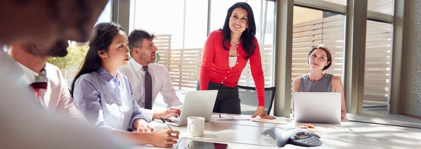 woman in red talking to a group of people in a conference room