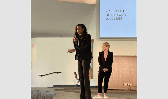 Dr. Rebecca Pianta, a university alum, holds a microphone while delivering a presentation alongside faculty member Dr. Marilou Ryder.