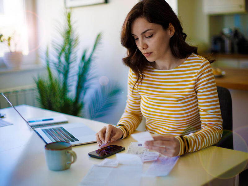 woman sitting at table with phone and laptop