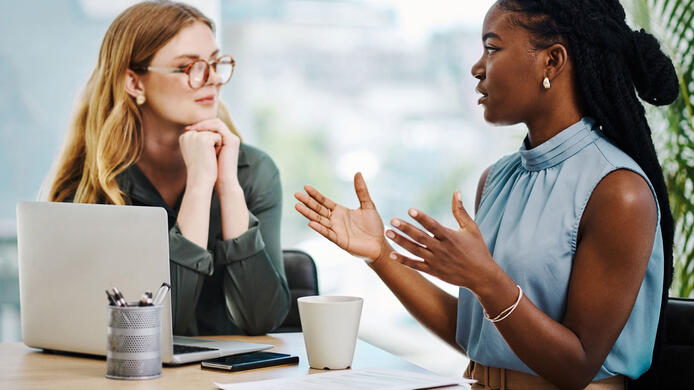 Two diverse businesswomen having a discussion to share ideas and plans while working together in an office