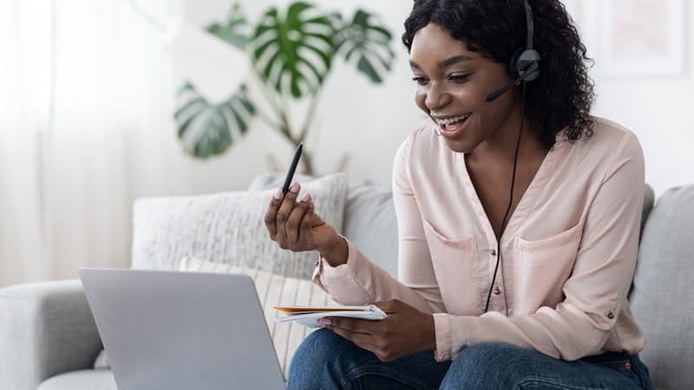 young female student interacting on laptop with headset on