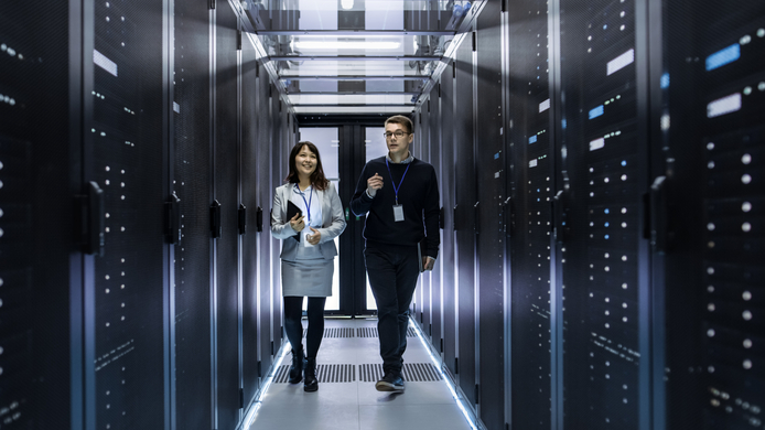 a male and female IT personnel walking through a computer/server room
