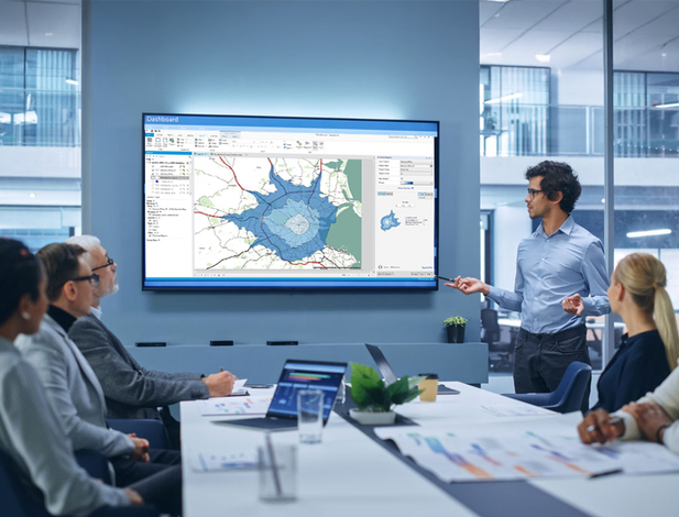 Office Conference Room Meeting Presentation: Latin Businessman Talks, Uses Wall TV to Show Company Growth with Big Data Analysis, Graphs, Charts, Infographics. Multi-Ethnic e-Commerce Startup Workers