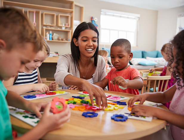 Teacher And Pupils Using Flower Shapes In Montessori School
