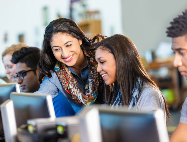 High school teacher teaching students on computer