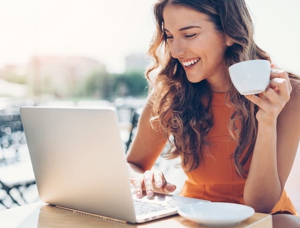 woman on her laptop at a cafe drinking coffee outdoors