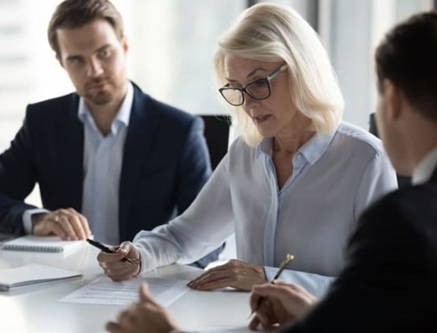 A business woman reviewing documents with two subordinates.