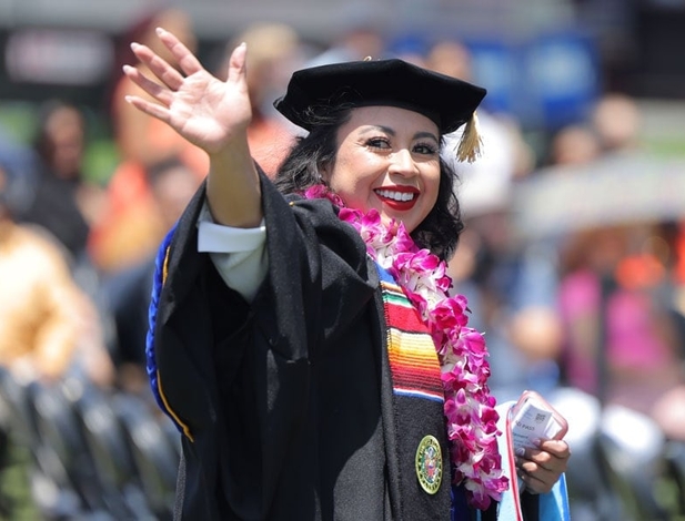 Hispanic female doctoral student from UMass Global at commencement waiving